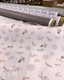 A soft pink fabric roll with parisian-themed pattern featuring scooters coffee cups and the eiffel tower for better tights