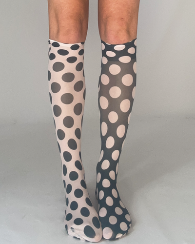 A pair of odd dot knee high socks in sheer white material with bold black polka dot pattern