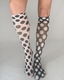 A pair of odd dot knee high socks featuring sheer black and cream fabric with a bold polka dot pattern